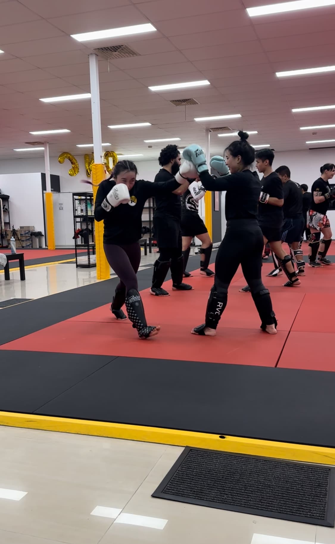 Two students exchanging punches in gloves and shin guards